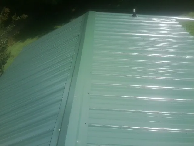 New green metal panels meeting at the ridge of a roof — Flat Roof Repair work by our crew in Concho