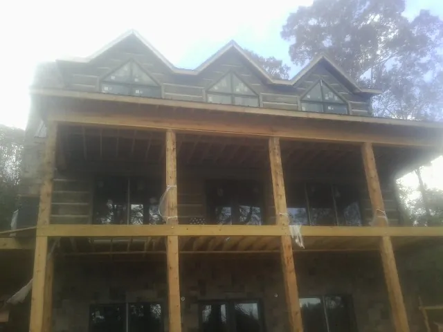 Dormers and porch framing on a large log home under construction — Roof Coating work by our crew in Concho