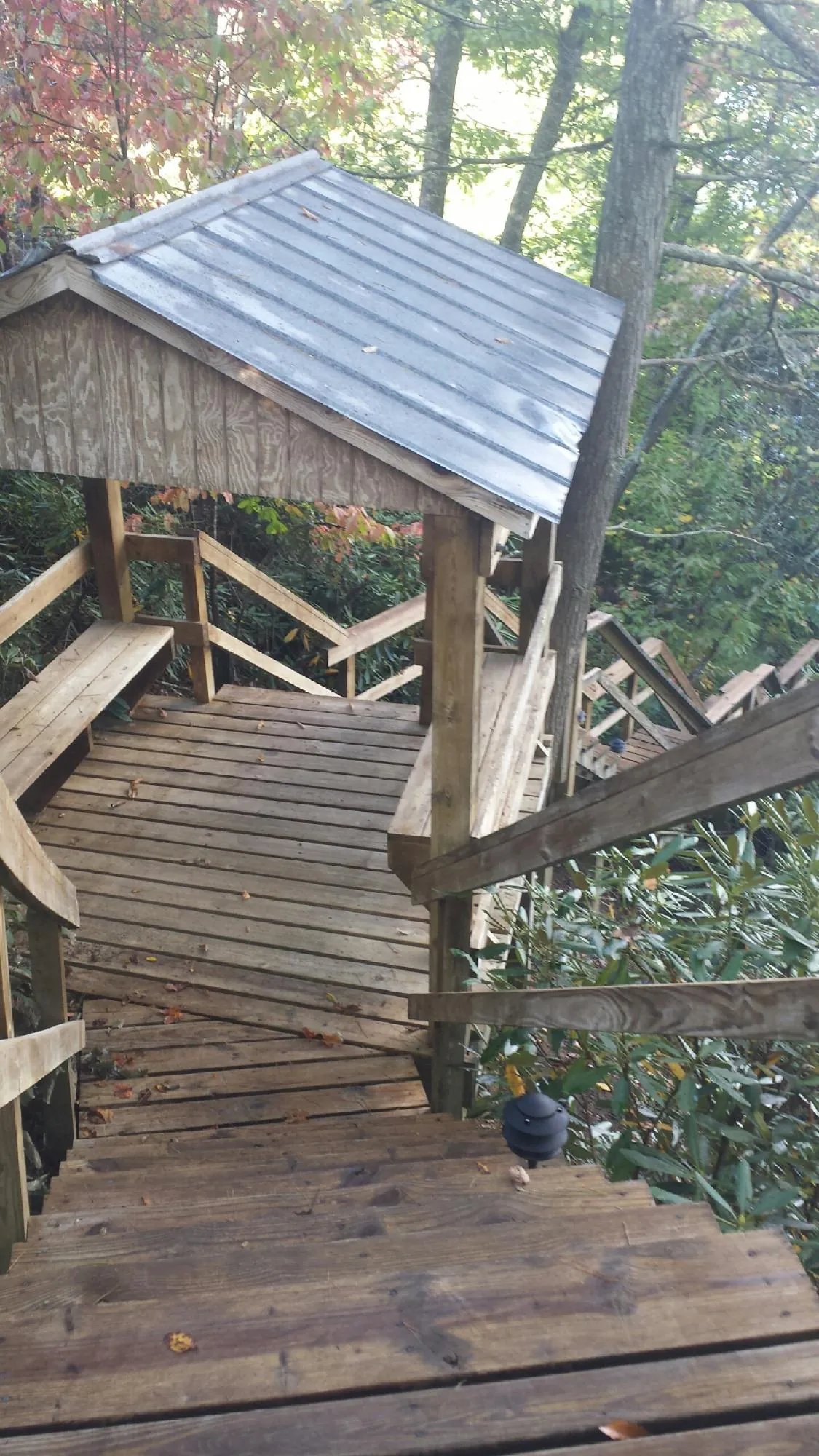 Metal roofed shelter over wooden steps on a wooded walkway — Skylight Repair & Installation work by our crew in Concho